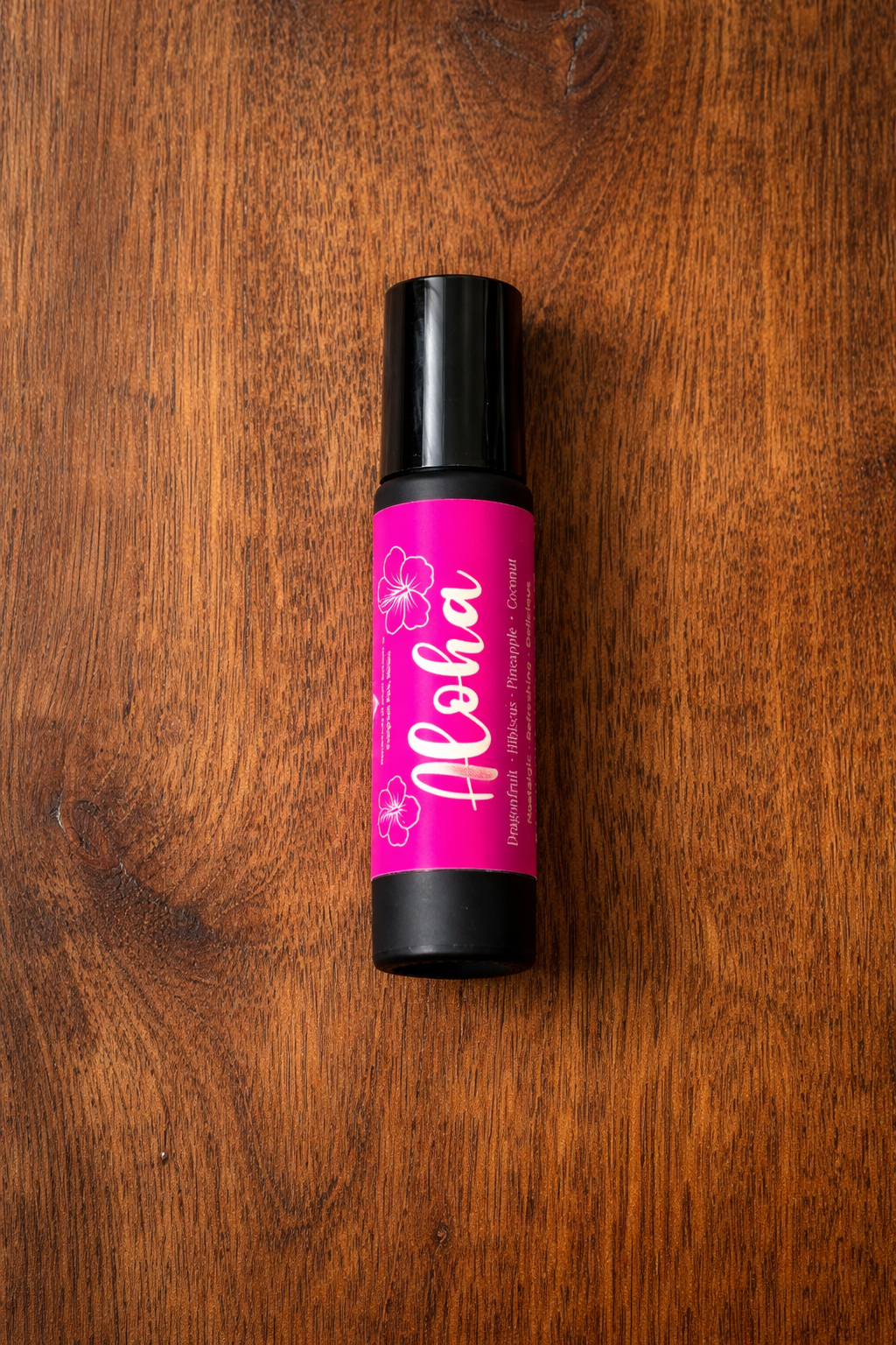 Pink and black bottle labeled 'Aloha' on a wooden surface