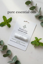 White Breathe Easy Nasal Inhalation Stick in blister packaging surrounding by peppermint and eucalyptus leaves with "pure essential oils" overlay.