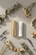 White cylindrical Breathe Easy Inhaler on a linen surface next to a lipstick tube for size reference.