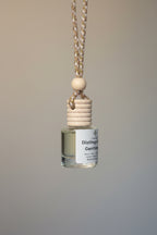Small bottle with a wooden cap hanging by a jute cord on a neutral background. 