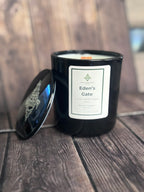Black candle with 'Eden's Gate' label on a wooden surface