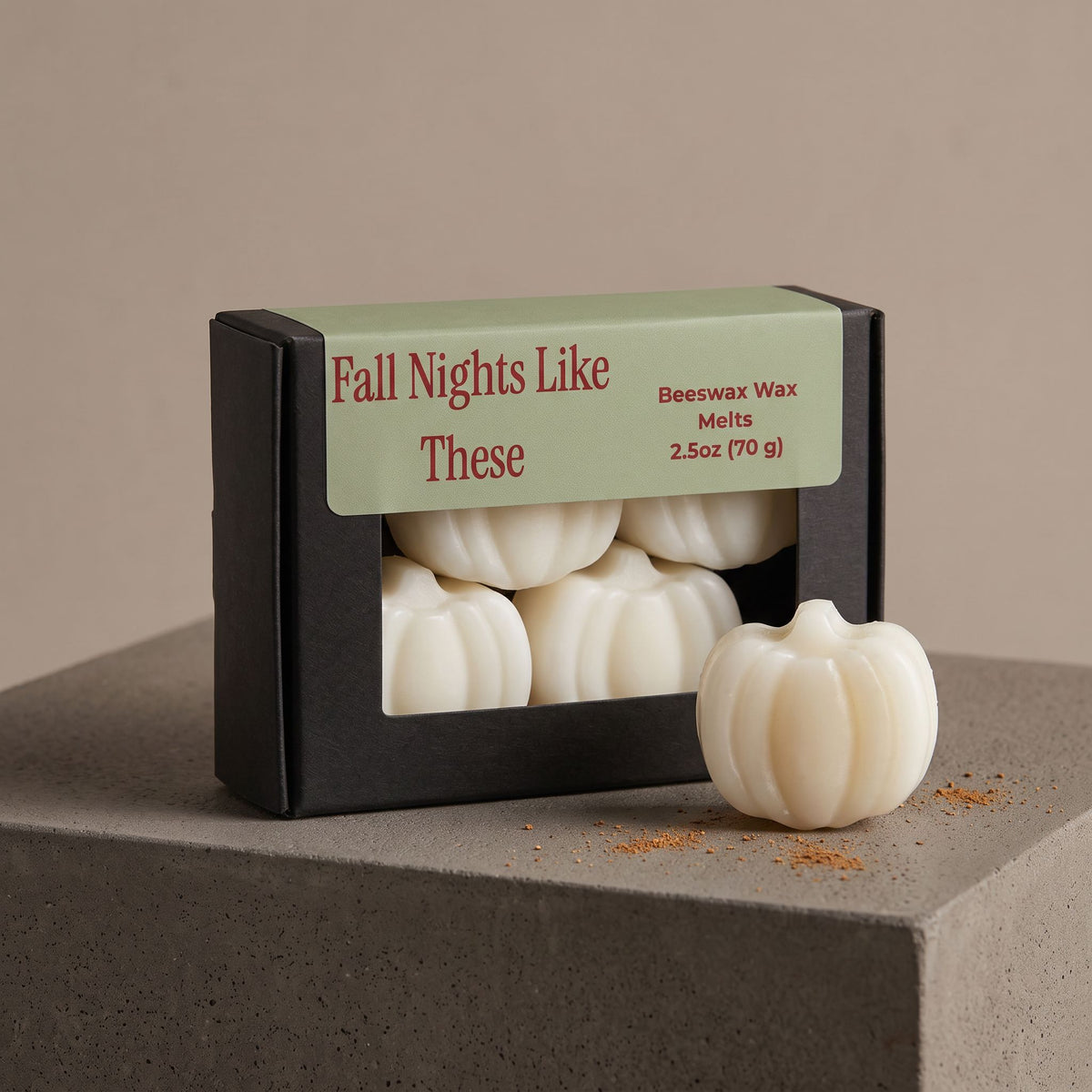 A black box of pumpkin-shaped beeswax melts with a sage green label reading 'Fall Nights Like These' sits on a gray stone pedestal, with one white pumpkin melt placed in front.