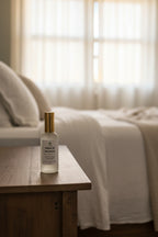 Frosted bottle labeled 'Hope of Morning' on a nightstand in a serene bedroom.