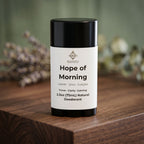 Deodorant with white label on a wooden surface with dried flowers in the background.