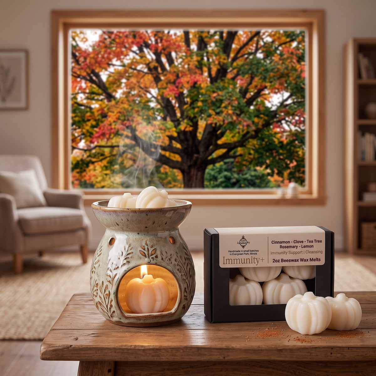 A wax melt product display in a cozy living room setting, featuring a ceramic leaf-patterned wax warmer with a glowing candle inside, several white wax melts, and a black box labeled 'immunity' in the scent 'Cinnamon - Clove - Blueberry - Lemon'.