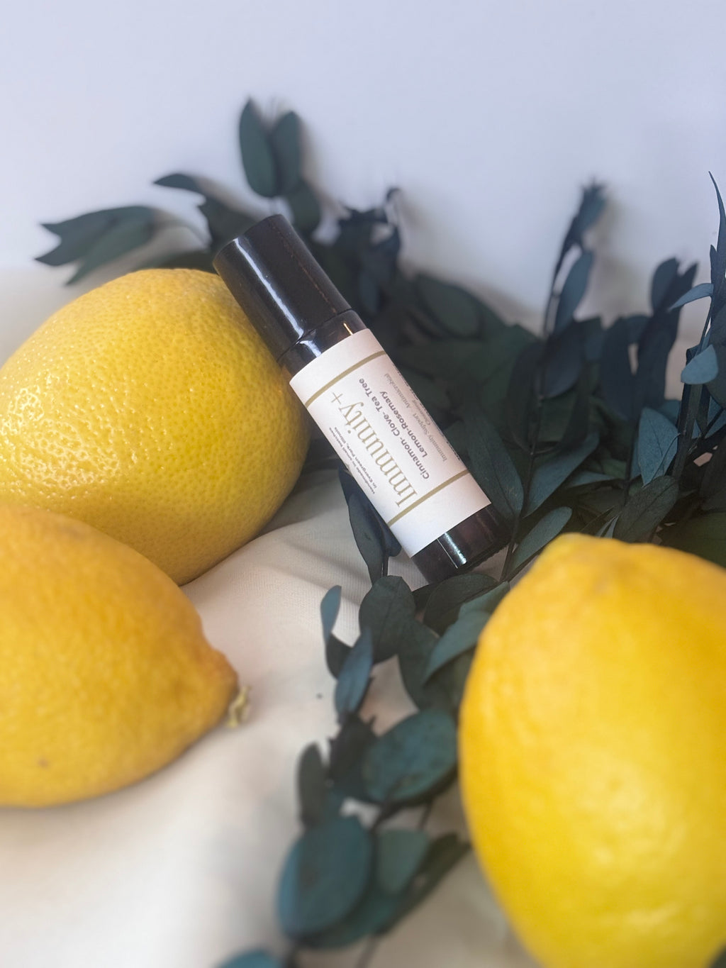 Skincare serum bottle with lemons and green leaves on a white background