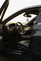 Car diffuser labeled 'Last One Standing' hanging from a rearview mirror in a car with the door open, leather seats and black interior.