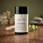 Natural deodorant stick labeled 'Last One Standing' on a wooden surface with plants and stones in the background.