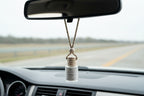 Candle labeled 'Last One Standing' with a natural cord hanging from a car mirror. 