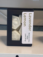 A black box of Lavender Lemon beeswax melts with a clear window showing the white hexagonal wax melts inside, set on a light wood surface.