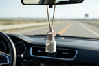 Small glass diffuser bottle labeled 'Lavender Lemon' with a cord hanging from a car mirror.