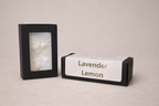 Black rectangular container with a photo on a beige background, next to a box labeled 'Lavender Lemon'.