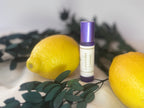 Roll-on bottle labeled 'Lavender Lemon' with two lemons and green leaves on a cream linen background.