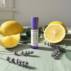 Roll-on bottle labeled 'Lavender Lemon' with lemons, greens and lavender on soft sage linen, showing the soothing benefits of the roller blend. 