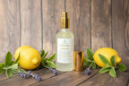 Lavender Lemon spray bottle with gold cap and container on wooden surface surrounded by lemons and greenery