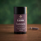 Luxe Cashmere deodorant container on a wooden surface with a blurred green background