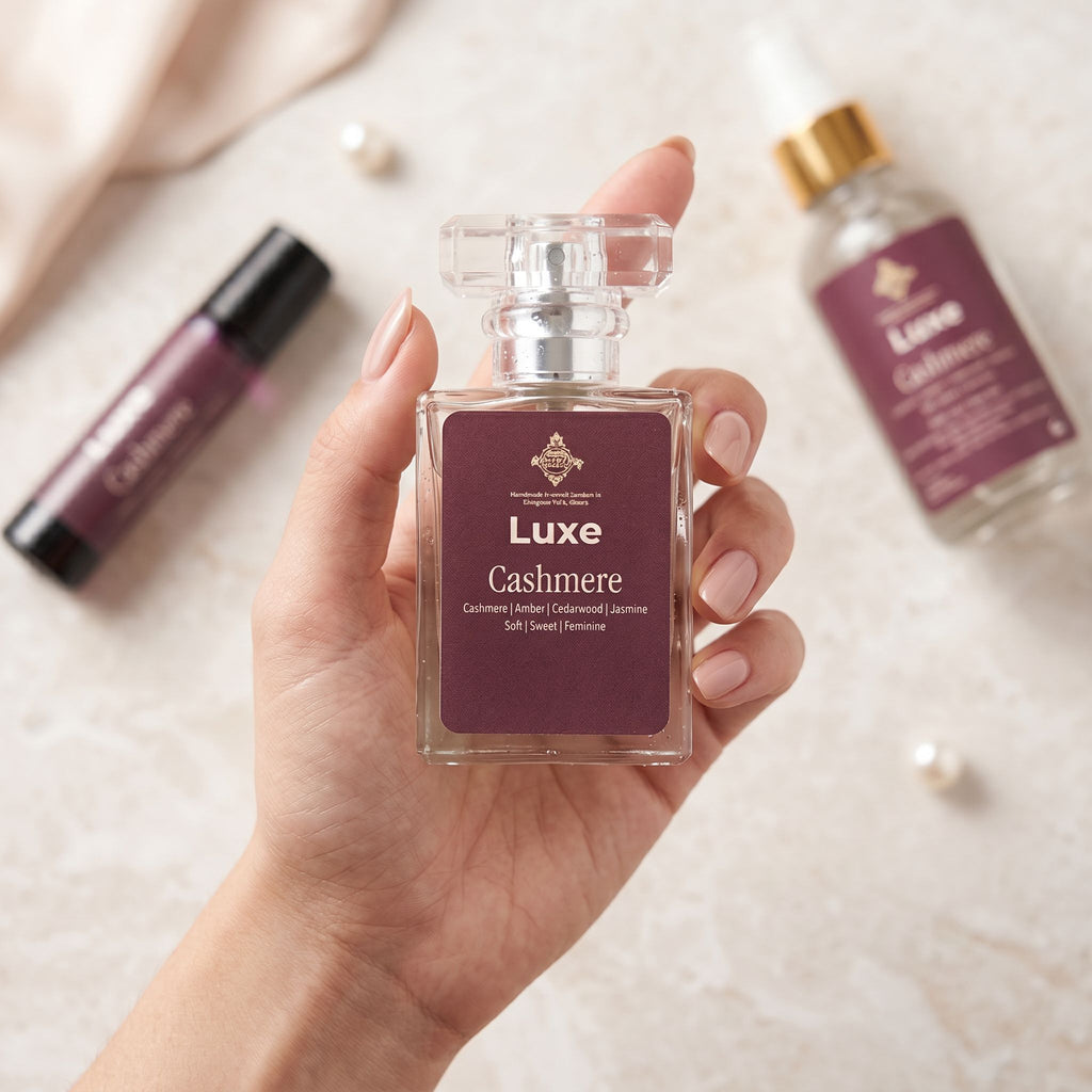 Hand holding a Luxe Cashmere perfume bottle with other perfume bottles in the background.