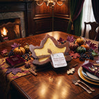 A fall-themed scented candle shaped like a maple leaf sits on a wooden dining table surrounded by autumn decorations including pumpkins, fall leaves, cinnamon sticks, and a small book labeled 'Puddie Penny'.