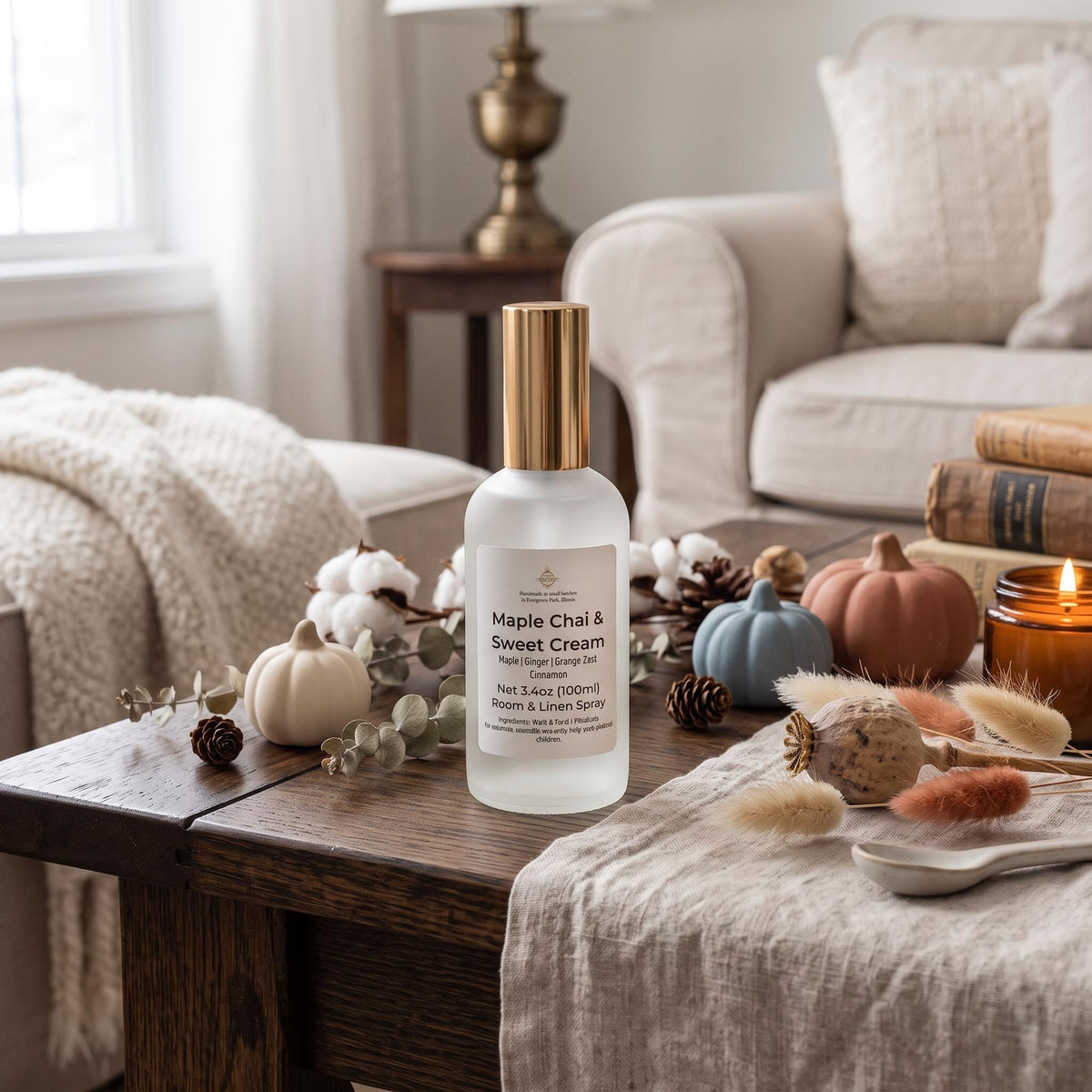 A frosted glass bottle of Maple Chai & Sweet Cream Aesop body wash with a gold cap, styled on a rustic wooden table in a cozy living room setting with autumn decorations.