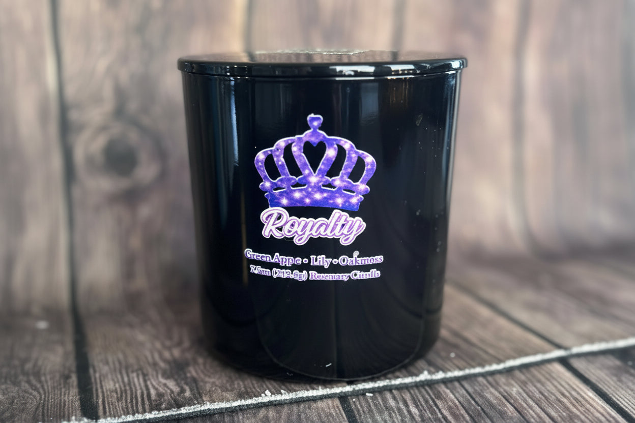 Black candle vessel with title Royalty on wooden surface.