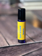 Roll-on bottle labeled 'Sun-kissed Jeans' on a wooden surface