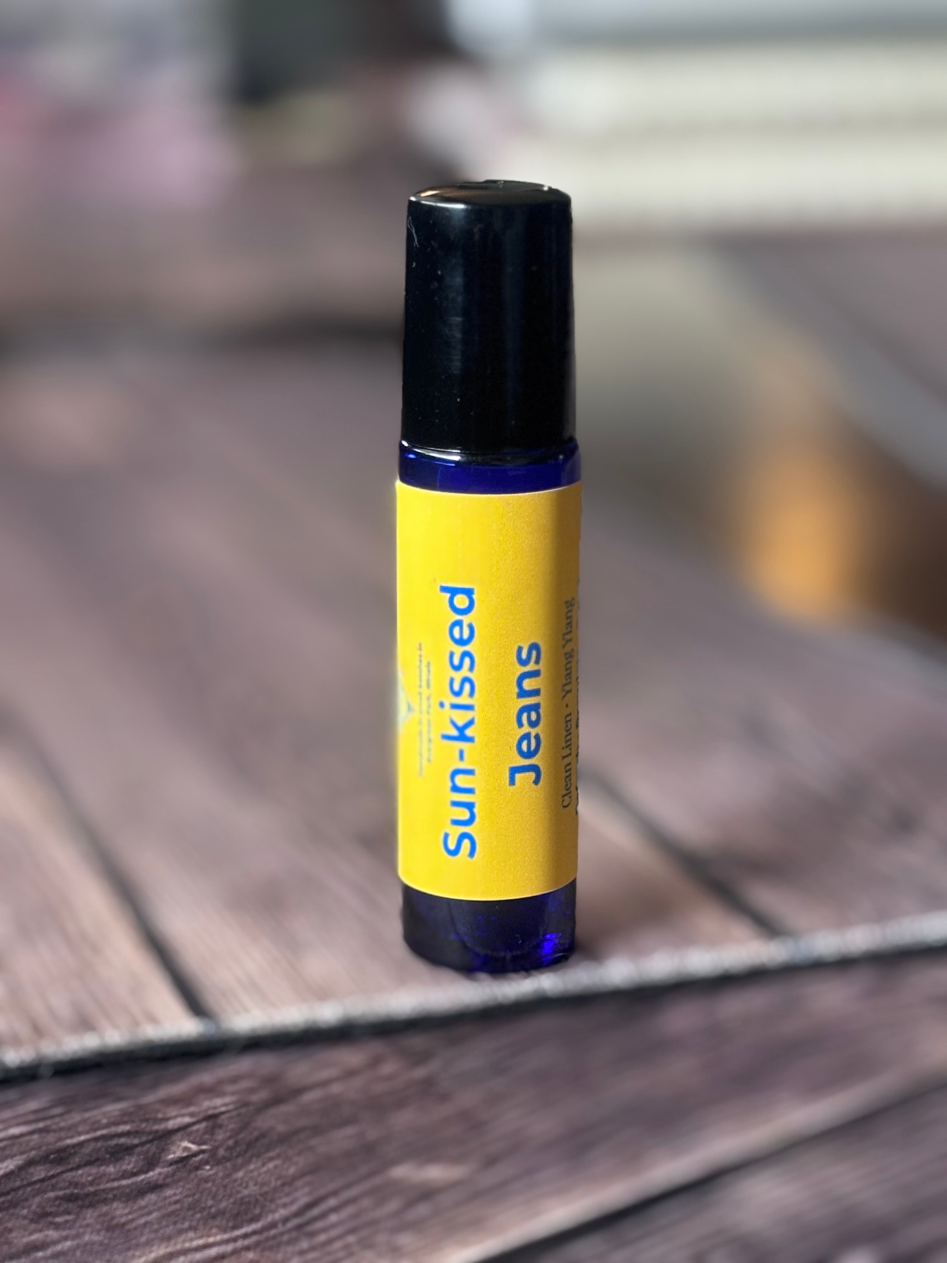 Roll-on bottle labeled 'Sun-kissed Jeans' on a wooden surface