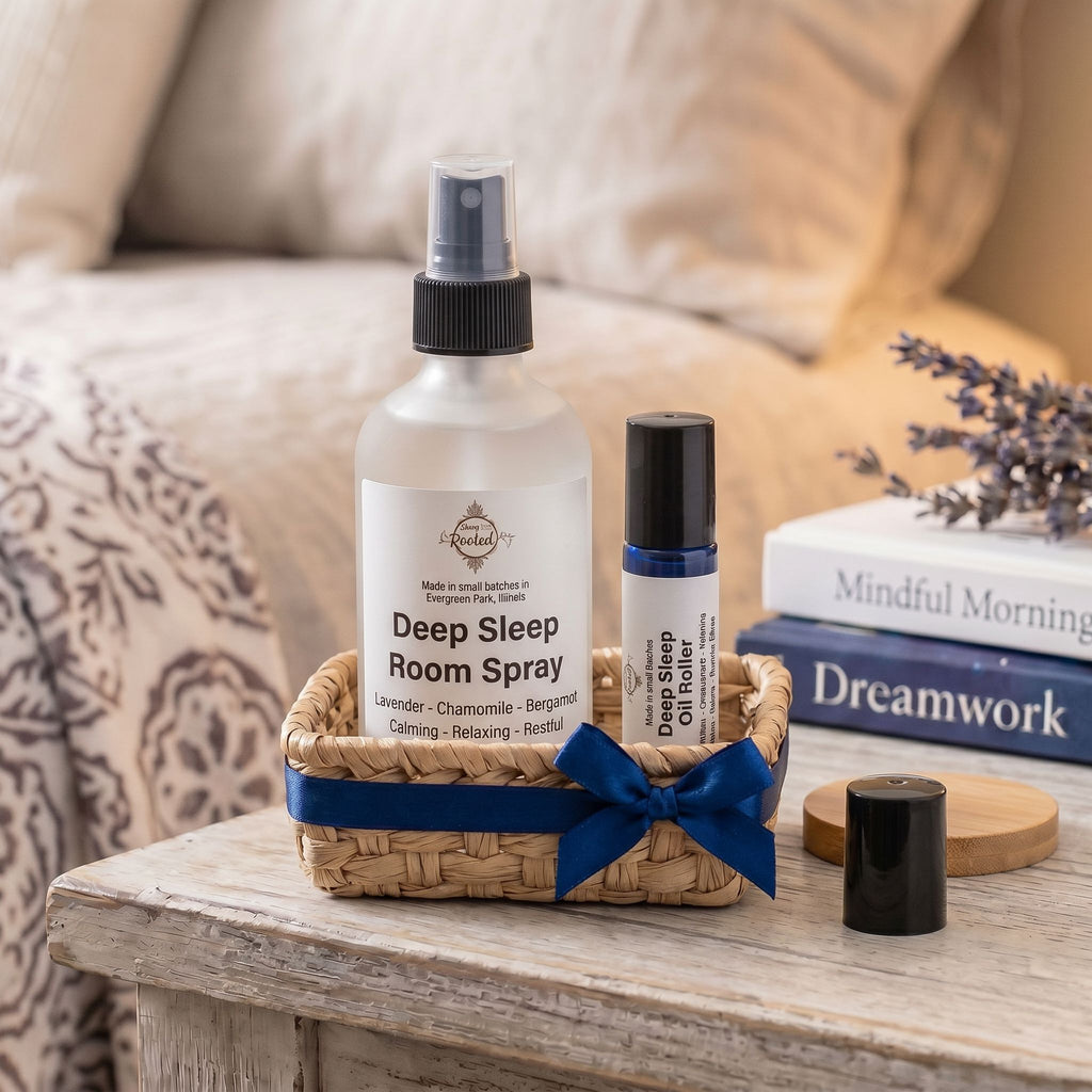 Clear Spray bottle with a label that says Deep Sleep in a basket next to a roller with the same.  Basket on a night stand next to a bed with soft lighting.