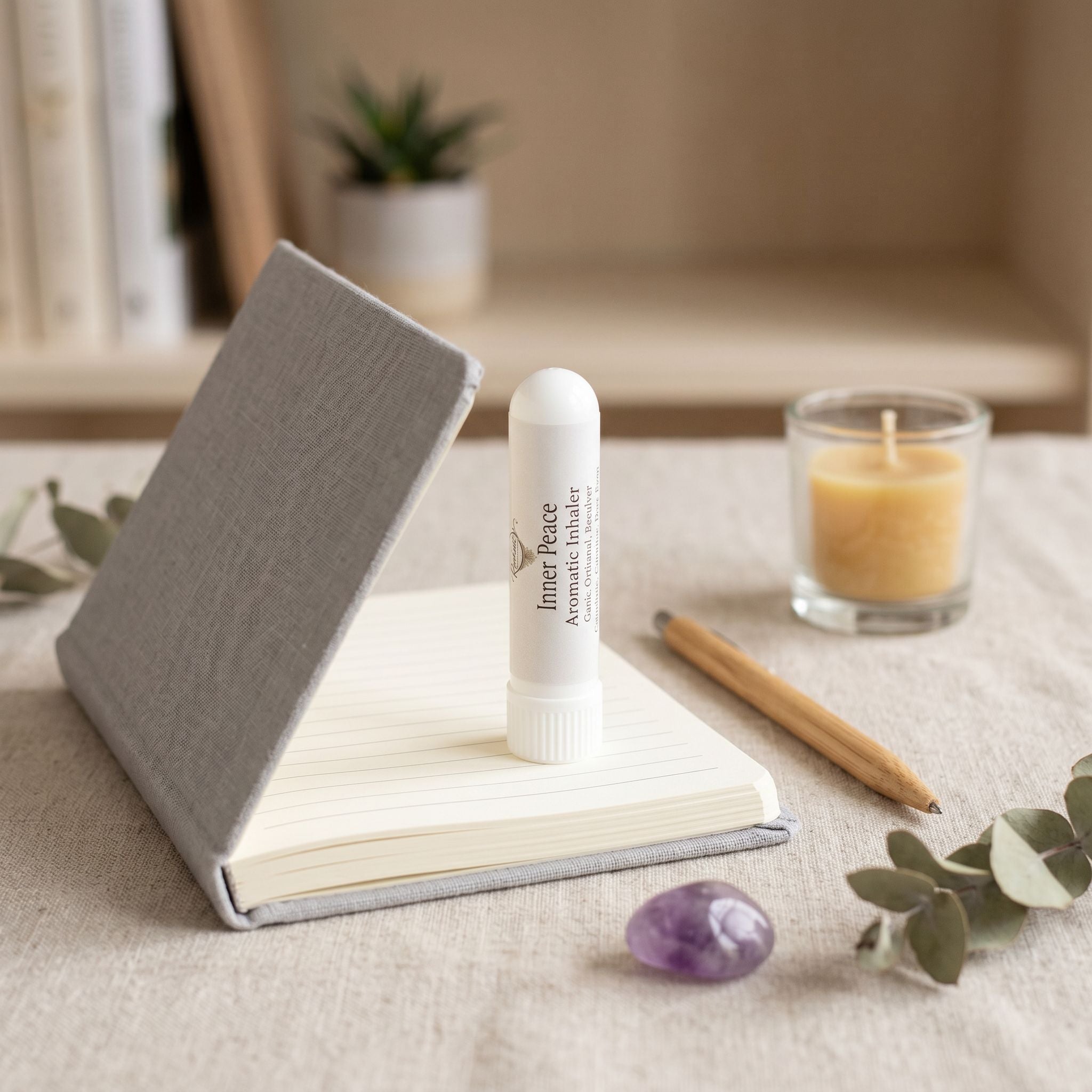Inner Peace nasal inhaler on a notebook with a linen, botanicals and a small candle in the background