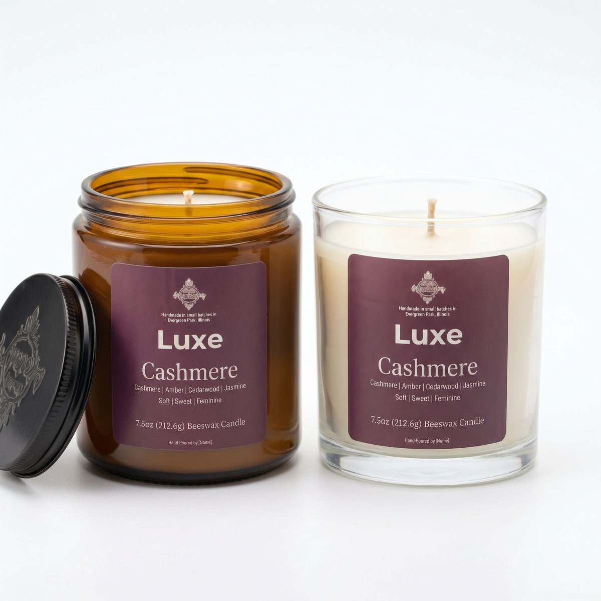 Two LuxE Cashmere scented candles on a white background, one in an amber glass jar with its black lid leaning beside it, and one in a clear glass jar with cream-colored wax.