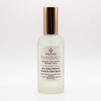 A frosted glass bottle of Immunity+ Room & Linen Spray with a metallic rose gold cap, shown on a clean white background.